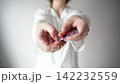 Static Shot Of Woman Extending Blister Pack Of Red Pills Toward Viewer In Bright Indoor Room  142232559