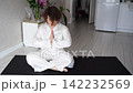 Static Shot Of Woman Meditating With Hands Clasped On Yoga Mat, Lifting Head From Bowed Pose  142232569
