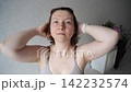 Static Shot Of Woman Adjusting Hair And Stretching Arms In Home Bedroom Interior During Morning 142232574