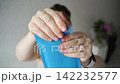 Static Shot Of Woman Tearing Open Blue Sachet And Removing Contents In Indoor Home Setting  142232577