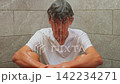 A teenage boy sits in the shower alone water is pouring on him, with his head in his hands, upset and overwhelmed. The kid is feeling upset, emotional, and mentally struggling 142234271