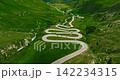 Establishing shot of cars on road trip across the mountains of Switzerland drive along hairpin turns. Aerial drone view winding mountain road 142234315