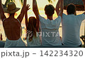 A friendly family watches the sunset on the shore of a tropical beach near the Indian Ocean in a grove of tropical palms. Silhouettes of a group of joyful people in the backlight at sunset 142234320