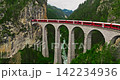 Aerial video of the red train traversing the Landwasser viaduct. The Swiss Express travels through the green meadows and mountains of Switzerland. Passenger transportation in Switzerland 142234936