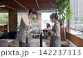 一對年輕的商務人士，一男一女，在咖啡館的站立式桌子旁開會。 142237313