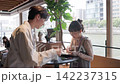 一對年輕的商務人士，一男一女，在咖啡館的站立式桌子旁開會。 142237315