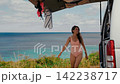 Young woman taking her surfboard out of a van parked near the beach 142238717