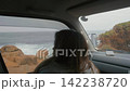 Woman looking at the Pacific Ocean from inside a car 142238720