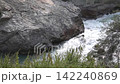 Powerful river flowing through rugged rocky landscape with lush greenery 142240869