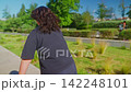 A group of individuals with similar attire strolls through a vibrant park, showcasing a lively atmosphere filled with greenery and bright sunlight in an outdoor setting. 142248101