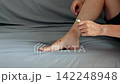 Person applying medicinal cream to a small skin injury on their ankle 142248948
