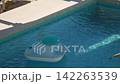 Inflatable pool floats in private villa pool during the summer. Sunlight reflects off surface of the water. Light plays on blue tiled bottom underwater. Gentle breeze. Pula, Croatia - August 15, 2026 142263539