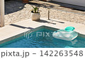 Inflatable pool floats in private villa pool during the summer. Sunlight reflects off surface of the water. Light plays on blue tiled bottom underwater. Gentle breeze. Pula, Croatia - August 15, 2026 142263548