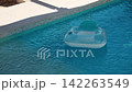 Inflatable pool floats in private villa pool during the summer. Sunlight reflects off surface of the water. Light plays on blue tiled bottom underwater. Gentle breeze. Pula, Croatia - August 15, 2026 142263549
