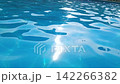 Close up of water caustics in deep blue swimming pool, gentle ripples with glinting sunlight reflections, clear azure water motion in outdoor pool, relaxing summer resort background, slow motion 142266382