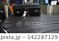 Baggage conveyor at an airport is moving suitcases, people are waiting, 4k 142287129