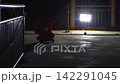 Construction Worker Grinding Surface with Angle Grinder at Night Under Bright Spotlight 142291045