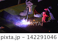 Welder Performing Stick Arc Welding on Metal Floor Surface Close Up With Bright Sparks in Industrial Environment 142291046