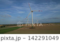 Title: Aerial View of Modern Wind Turbines Standing in Agricultural Fields Under Blue Sky 142291049