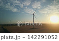 Aerial View of Wind Turbines in Agricultural Field Against Bright Sunset Sun Flare 142291052