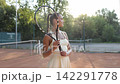 Young female tennis player smiling with racket on outdoor clay court 142291778