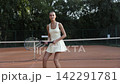 Young female tennis player moving into ready position on clay court 142291781