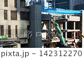 A cityscape with heavy machinery working at a building demolition site. 142312270