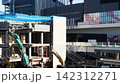 A cityscape with heavy machinery working at a building demolition site. 142312271