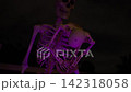 Close-up of a Halloween skeleton under purple lighting at night. The skeleton holds a small ghost decoration with rope, creating a spooky yard display. 142318058