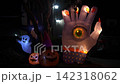 Close-up Halloween yard display at night with a giant inflatable hand with an eyeball, glowing ghosts, and jack-o'-lanterns. A suburban house and driveway show festive lights and decorations for trick 142318062