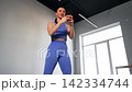 Portrait of charming active fit woman in sportswear making video call, communicating online with friend using mobile phone, sharing about workout routine while exercising squats in fitness studio. 142334744