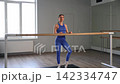 Active graceful fitness woman in sportswear exercising bend in standing split, leaning on barre in health club, strengthening leg, back and abdominal muscles improving flexibility during workout. 142334747
