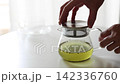 緑茶が入った透明なガラス急須から茶こし一体型の蓋を取り外す手元（動画素材） 142336760