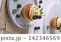 Vanilla cupcake with white frosting and fresh blueberries on white plate 142346569