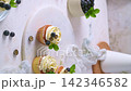 Delicious vanilla cupcakes with white frosting blueberries and mint on a textured surface 142346582