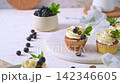 Fresh vanilla cupcakes with white cream frosting blueberries and mint on a white board 142346605