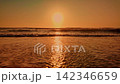 Low angle view of ocean waves washing onto a sandy beach during a golden sunset 142346659
