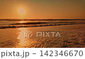 Golden sunset reflecting on ocean waves washing over a sandy beach 142346670