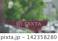 Raindrops are seen falling on a window. The background shows the green colors of trees and plants 142358280