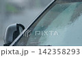 Heavy rain pours on car windshield in urban setting during late afternoon 142358293