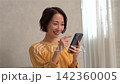 一個女人在客廳裡使用智能手機 142360005