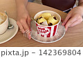 Popcorn Shaped Mousse Dessert with Creamy Filling Eaten by Young Woman with Spoon in Modern Cafe 142369804