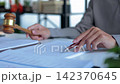 Lawyer hand holding wooden gavel during reviewing reading legal or case documents. 142370645