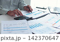Businessman working at office desk using calculator analyzing financial charts data in office. 142370647