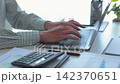 Businessman working in office typing on laptop with graph data and calculator at desk. 142370651