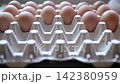 Close-up video of a hand selecting and inspecting brown chicken eggs arranged in a cardboard carton 142380959