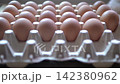 Close-up video of a hand selecting and inspecting brown chicken eggs arranged in a cardboard carton 142380962