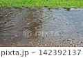 Child in blue rain boots jumping and splashing in a puddle 142392137