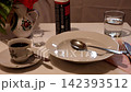 A simulation of an earthquake on a table with a cup of coffee, a glass of water, a plate, cutlery, and a vase of flowers, with everything shaking as if during an earthquake 142393512