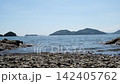 A coastal landscape of rocky shores and sandy beaches with gentle waves lapping against the shore. 142405762